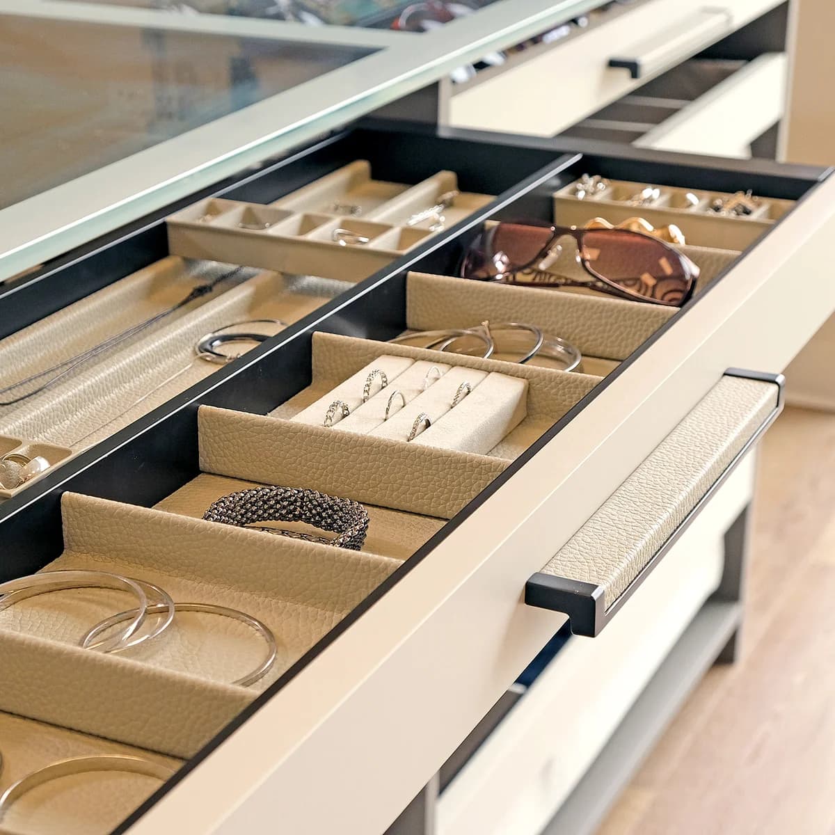 Jewelry and sunglasses arranged in lined drawer compartments