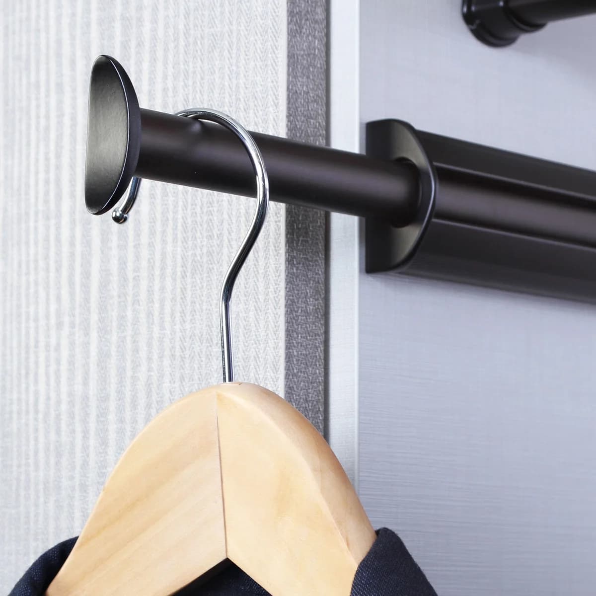 An extended valet rod holding a wooden clothes hanger